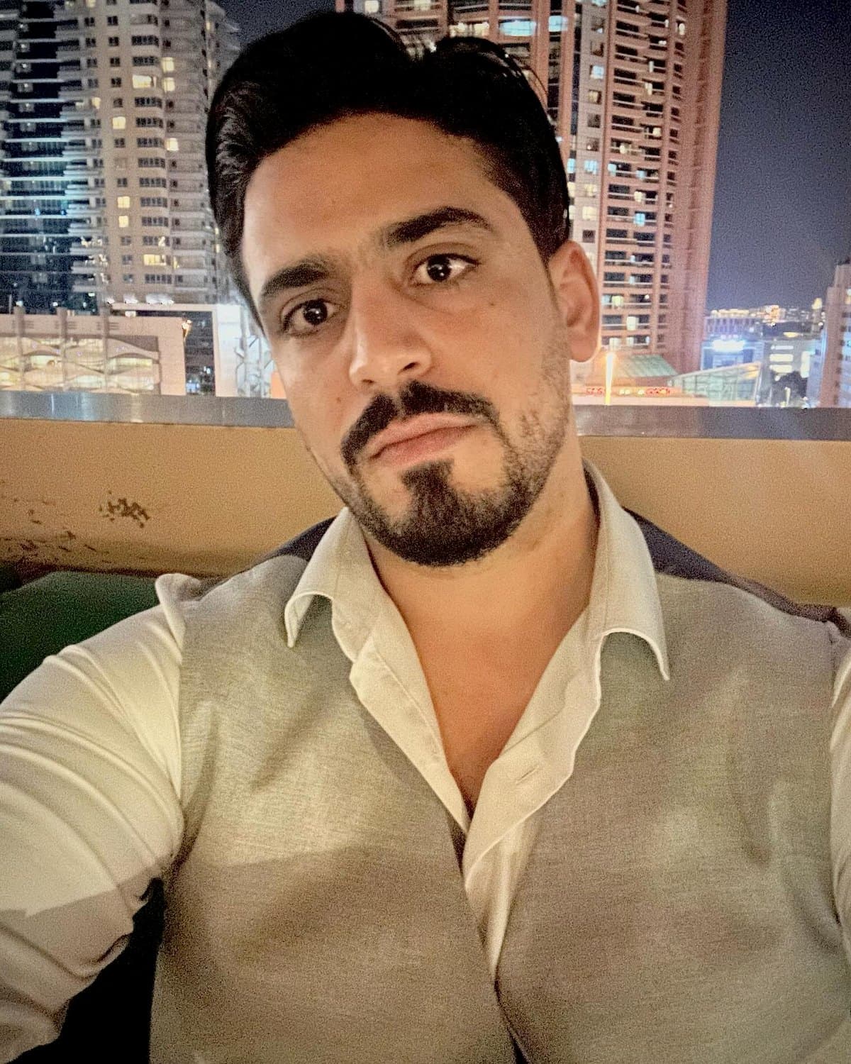 إيهاب عياد، المؤسس والرئيس التنفيذي لشركة إيهاب عياد العقارية، وخلفه أفق دبي ليلاً